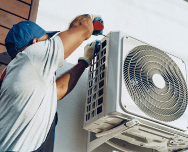 Repairman in uniform installing the outside unit of air conditioner close up