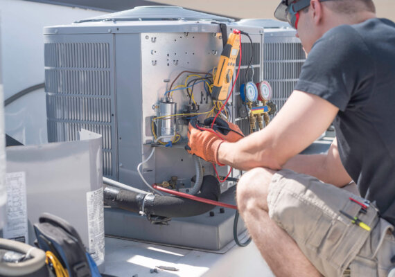 Hvac repair technician using a volt meter to test components on an air conditioner condenser.