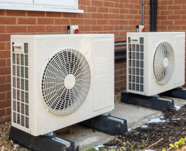 Two air source heat pumps installed on the exterior of a modern house