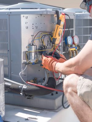 Hvac repair technician using a volt meter to test components on an air conditioner condenser.